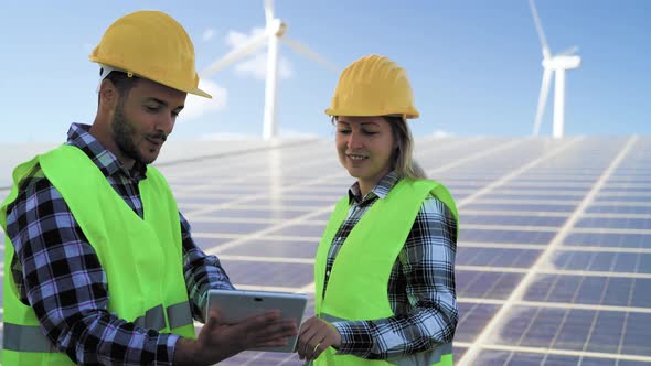 People working for alternative energy with wind turbine and solar panel alt