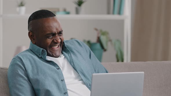 Adult African American Man Sitting Looking at Laptop Screen Puzzled Worried Funny Expression Froze alt