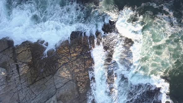Aerial over a rocky coastline and small town with waves breaking alt
