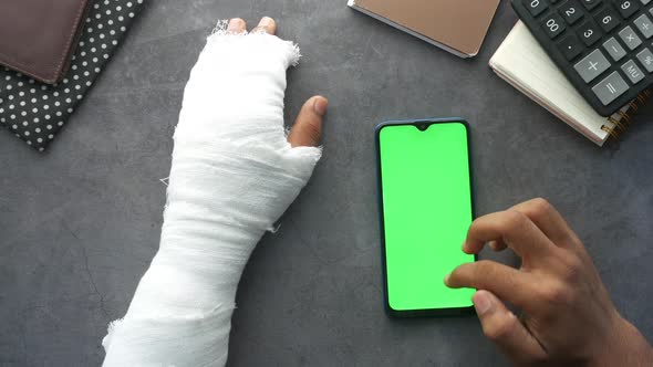 Injured Painful Hand with Bandage and Using Smart Phone alt