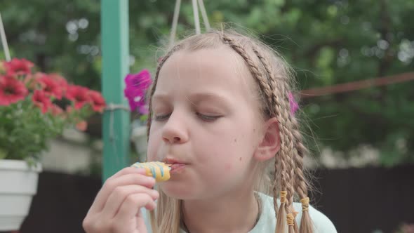 Young Girl with Pigtails with Appetite and Pleasure Eats Delicious Ice Cream