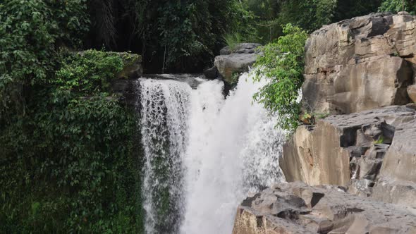 A Large Waterfall Surrounded By Jungle and Rocky Ledges Filmed in the Daytime