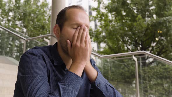 A Caucasian Man Acts Unhappy As He Sits on a Staircase in an Urban Area  Closeup From Below