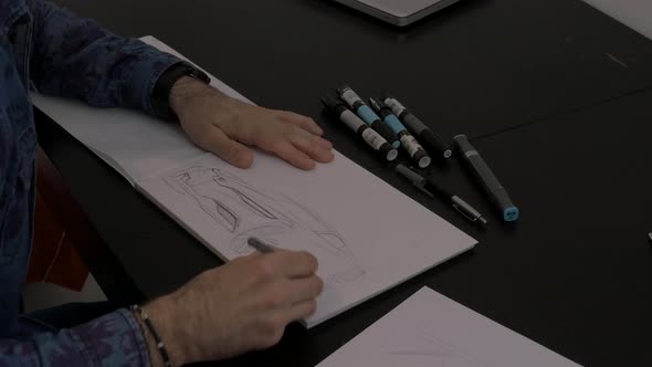 Artist's hands sketching the bumper of a car alt