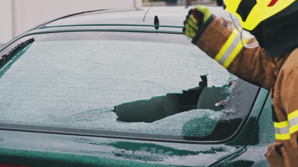 Car Accident Rescue, Firefighter Breaking the Glass on the Car. Close Up, Slow Motion Shot alt