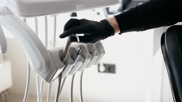 Closeup of a Male Dentist in Gloves Takes Tools Vacuum Equipment in the Dental Office Closeup alt