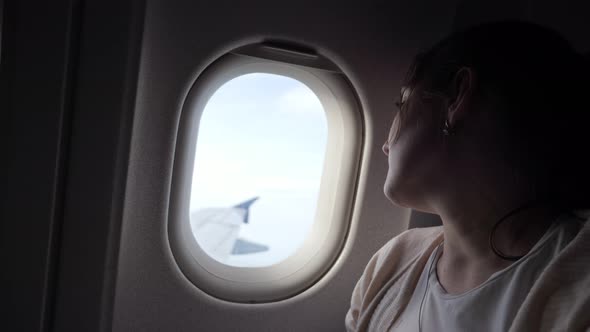 Portrait of Sleepy Tired Woman is Looking at Airplane Window Dirung Flight alt
