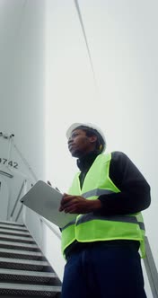 A Man in a Work Uniform is Diagnosing a Wind Turbine Using a Digital Tablet alt