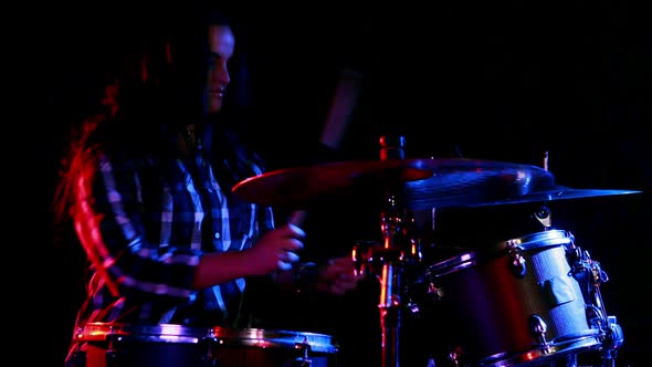 Female drummer playing on drum set alt