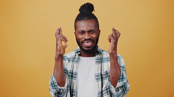 Young Dark Skinned Afro Man Looking Nervous Crossing Fingers Acting Like Praying for Luck alt