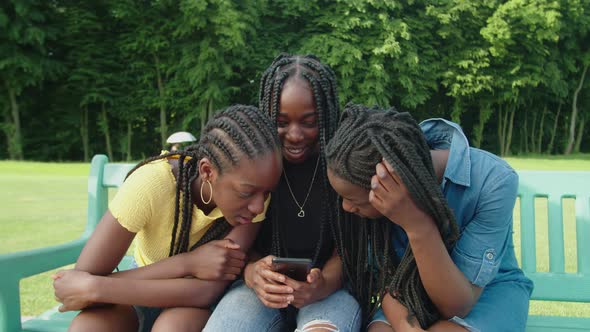 Lovely African Teenage Girls Watching Social Media Content Online on Phone alt