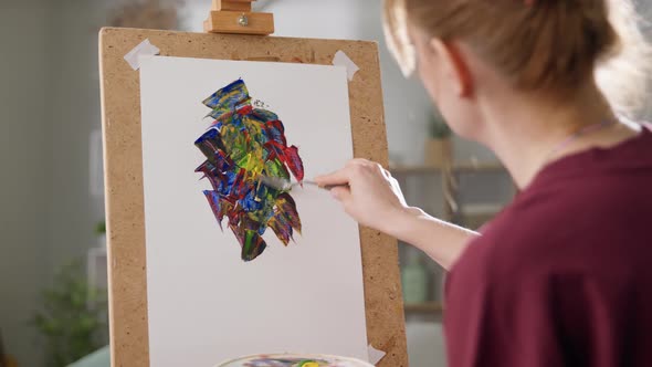 Young Woman Artist Draws a Picture with Oil Paints at Home in the Living Room alt