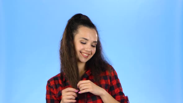 Pretty Young Woman Winding Hair on Finger and Looking Playfull alt