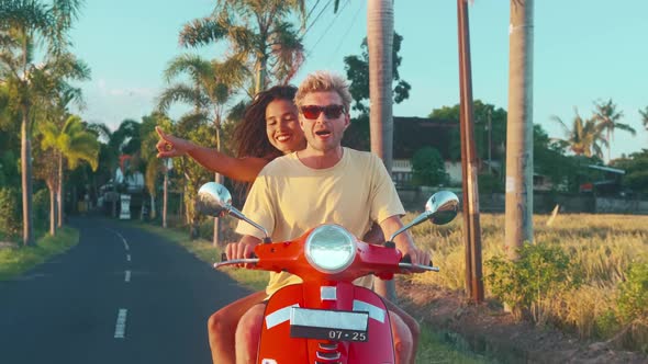 Young Couple in Love is Riding Retro Moped on Road in Tropics alt