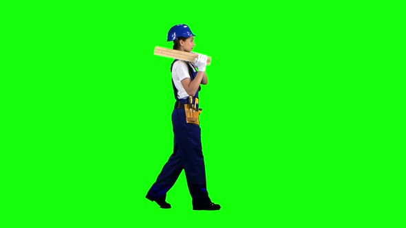 Construction Worker Wearing a Helmet Carries Three Wooden Boards. Green Screen. Side View alt
