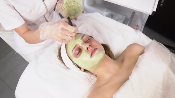 The Cosmetologist Slowly Applies a Clay Face Mask To the Client with a Brush