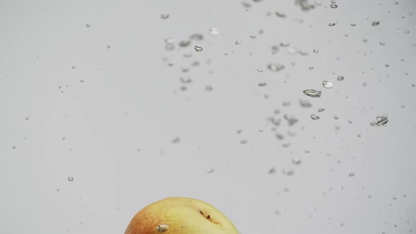 Fruits Red and Yellow Pears Falling Into Water with Splash and Air Bubbles White Background alt