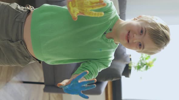 Boy with Down Syndrome with Yellow and Blue Paint on Hands