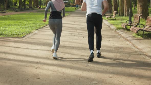Young Muslim Couple in Sport Clothes Standing in Start Position for Run at Green alt