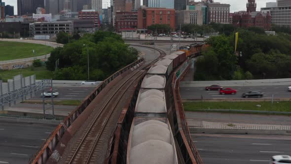Forwards Reveal of Freight Train Standing on Track Leading on Bridge Over Busy Highway alt