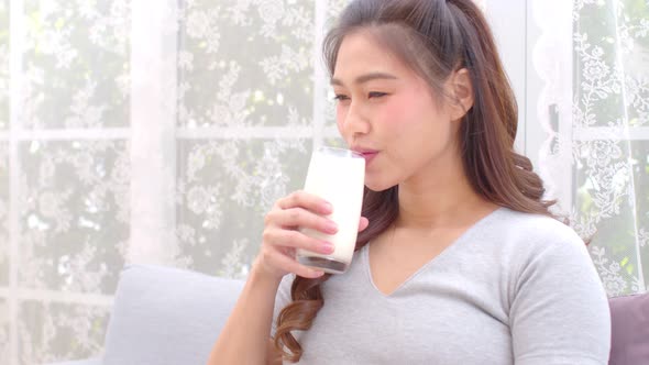 Healthy Young Asian woman Drinking milk with calcium for strong bone at home alt