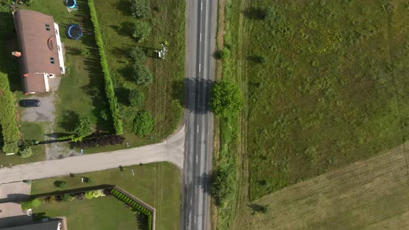 Aerial View of the Highway Going Through the Green Fields and Forests alt