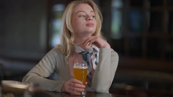 Gorgeous Slim Caucasian Young Woman Sitting at Bar Counter with Glass of Pale Lager alt