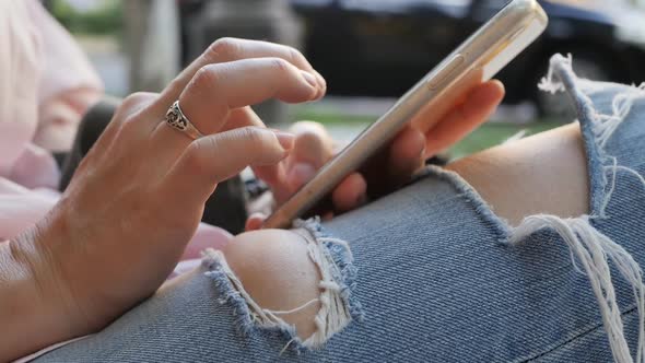 Female Hands with a Silver Ring and a Bracelet on the Wrist Use a Smartphone Holding and Leaning on