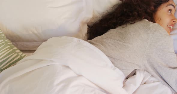 Happy young woman lying on bed using her mobile phone 4K 4k alt