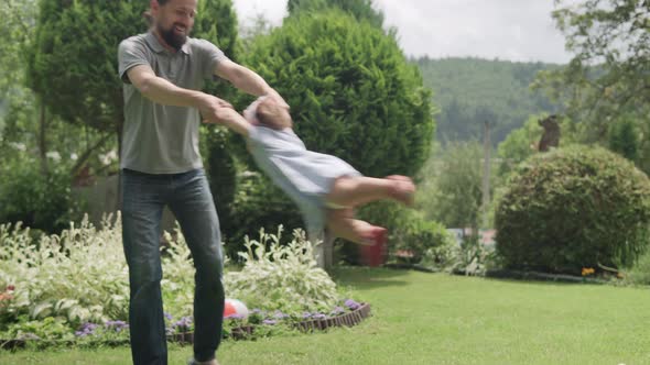 Happy Family Funny Dad with Beard Swinging Kids Around Playfully By Arms alt
