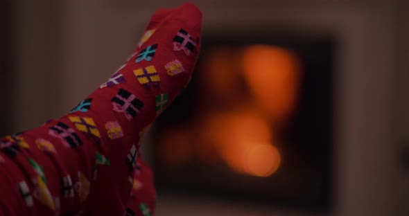 Woman Wearing Warm Wool Socks Lying By the Fireplace at Christmas alt
