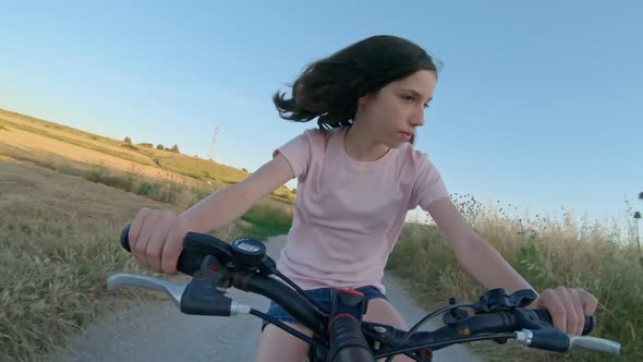 POV of a young girl enjoying a bicycle ride on the rural countryside alt