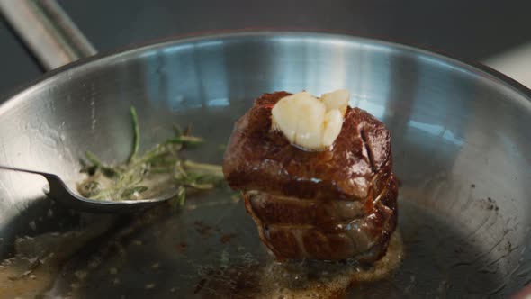 Close-up of a filet mignon being cooked in a frying pan alt