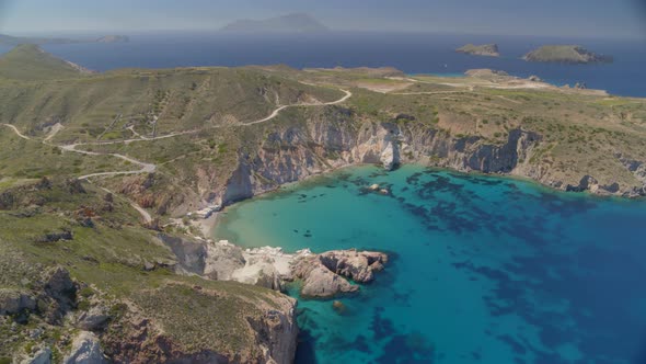 Aerial Pan of a Bay Surrounded by Cliffs on the Blue Aegean Sea in Milos Greece alt