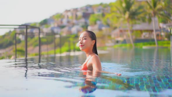 Young asian woman enjoy around outdoor swimming pool for leisure alt