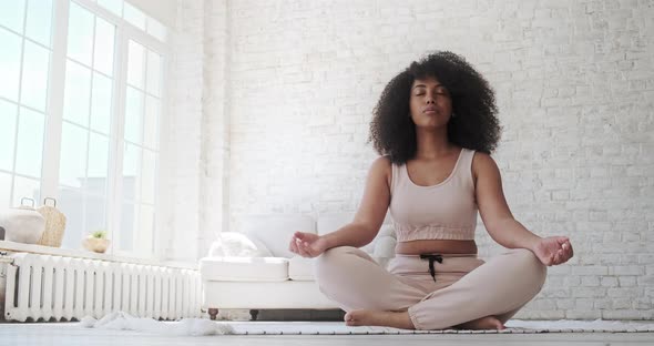 A Black Woman Sits in a Lotus Position alt
