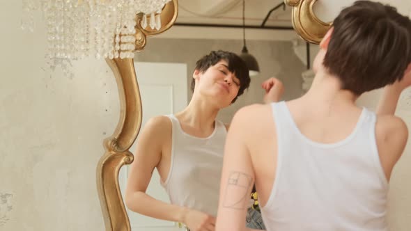 Happy woman dance in front mirror and enjoys herself reflection at home. alt