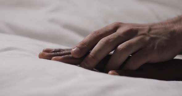 Multi-ethnic Couple in Love Lying in Bed Together. Close Up. Womans Hand Is Lying on a Bed, Mans alt