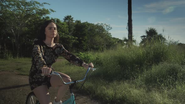 Girl Riding A retro Bicycle in nature. Front View. Jungle And Clouds In The Background alt