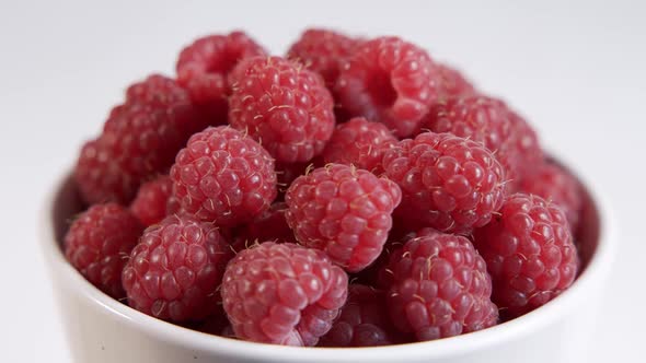 Ripe Raspberries in a White Plate on a White Background