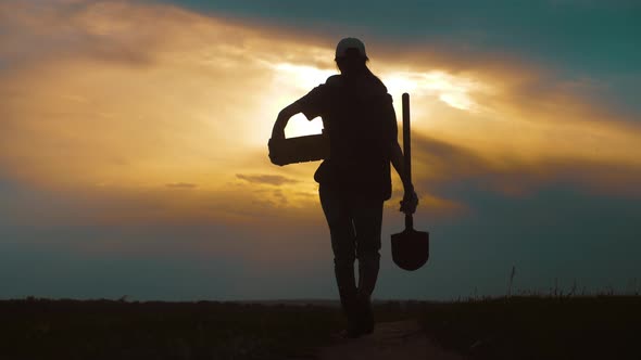 Woman Farmer Holding Shovel in His Hand Walking Across Green Field a Pile of Dirt Soil alt