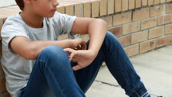 Sad schoolboy sitting alone on staircase alt