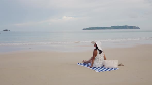 Young Woman Relaxing On Beach Towel Looking Out To Sea alt