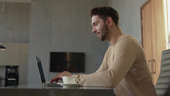 Attractive man typing message to friends from office at home alt