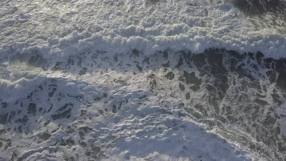 Aerial Drone Shot of Beach with Crashing Waves and Rocks alt