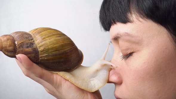 Pretty woman with big african snail on her face. 