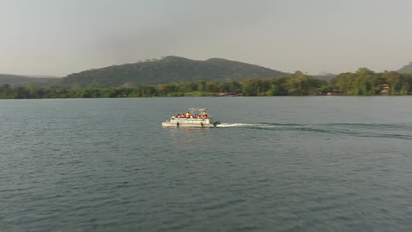 cruise boat with people on river with hill view alt