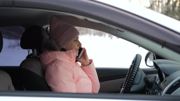 Female Talking on Phone in Her Car in Winter Day alt