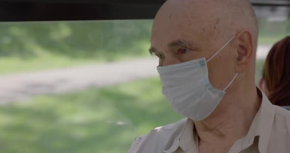 Senior Man in Medical Mask is on a Bus