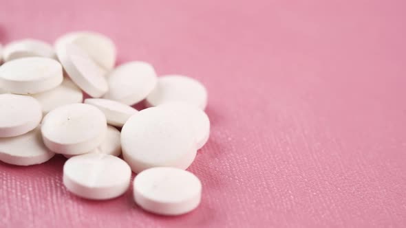 Close Up of White Color Medical Pills on Pink Background alt